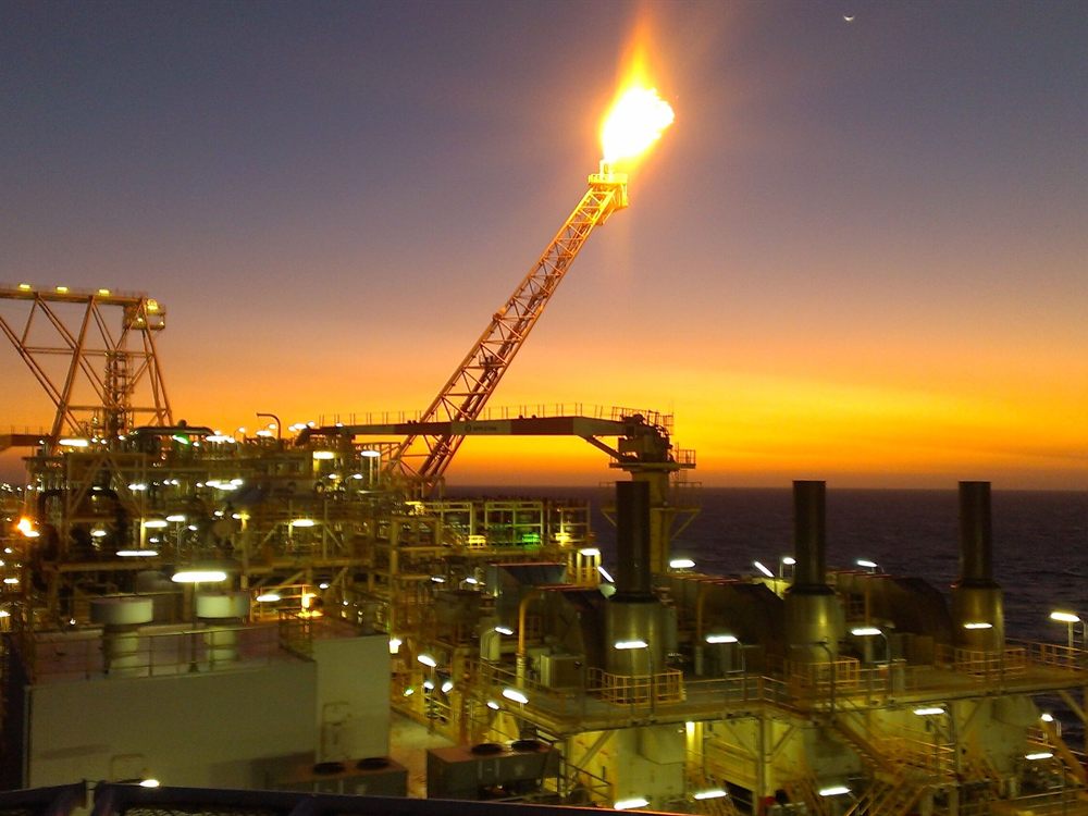 Offshore oil and gas platform with flare stack at sunset